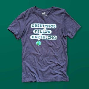 A heather blue t-shirt with a design that says Greetings Fellow Earthling