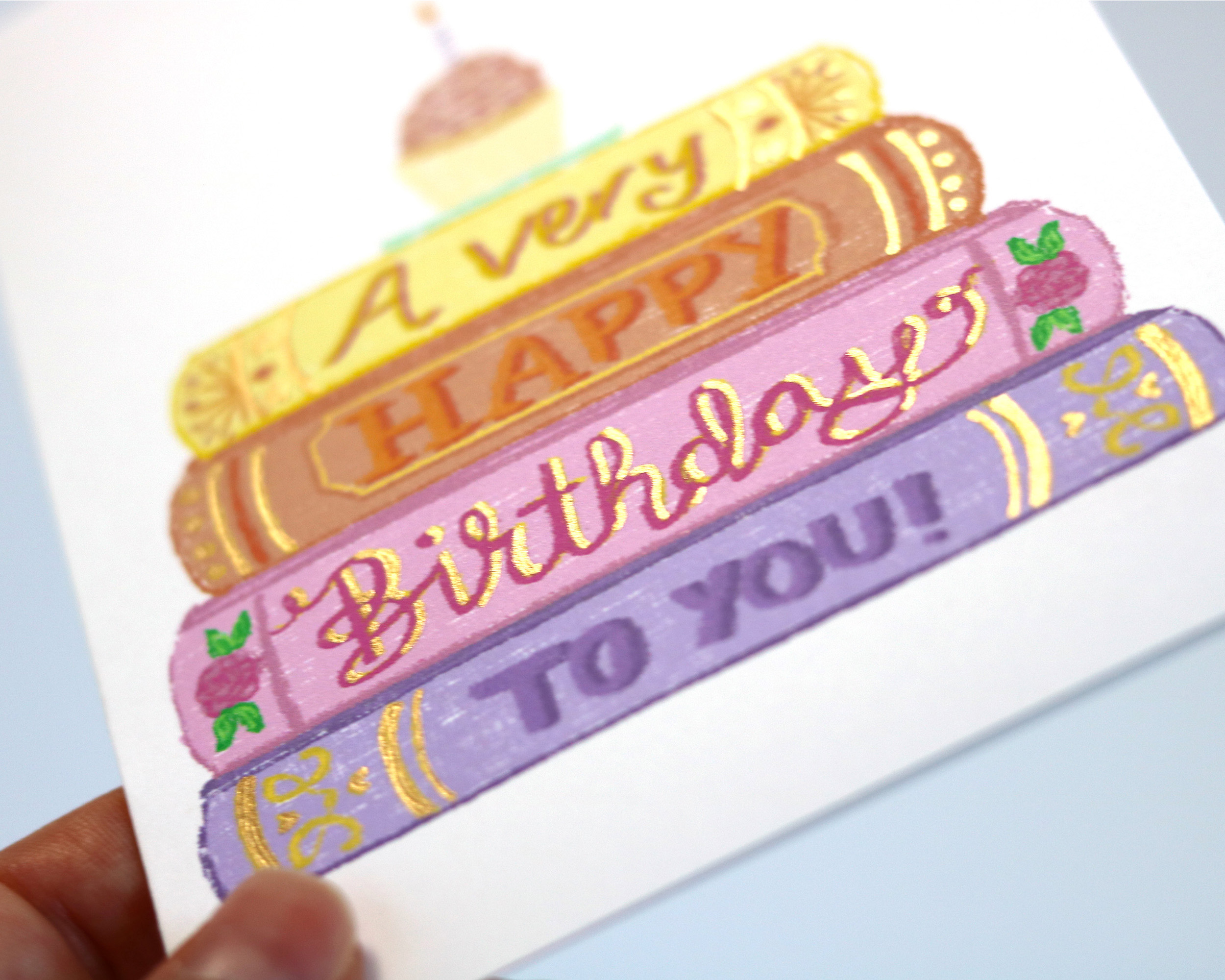 Close up of illustrated stack of books embellished with hand painted gold details.