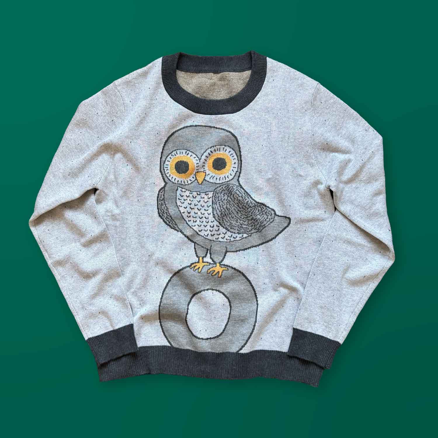 A gray sweater with a dark gray owl design on the front