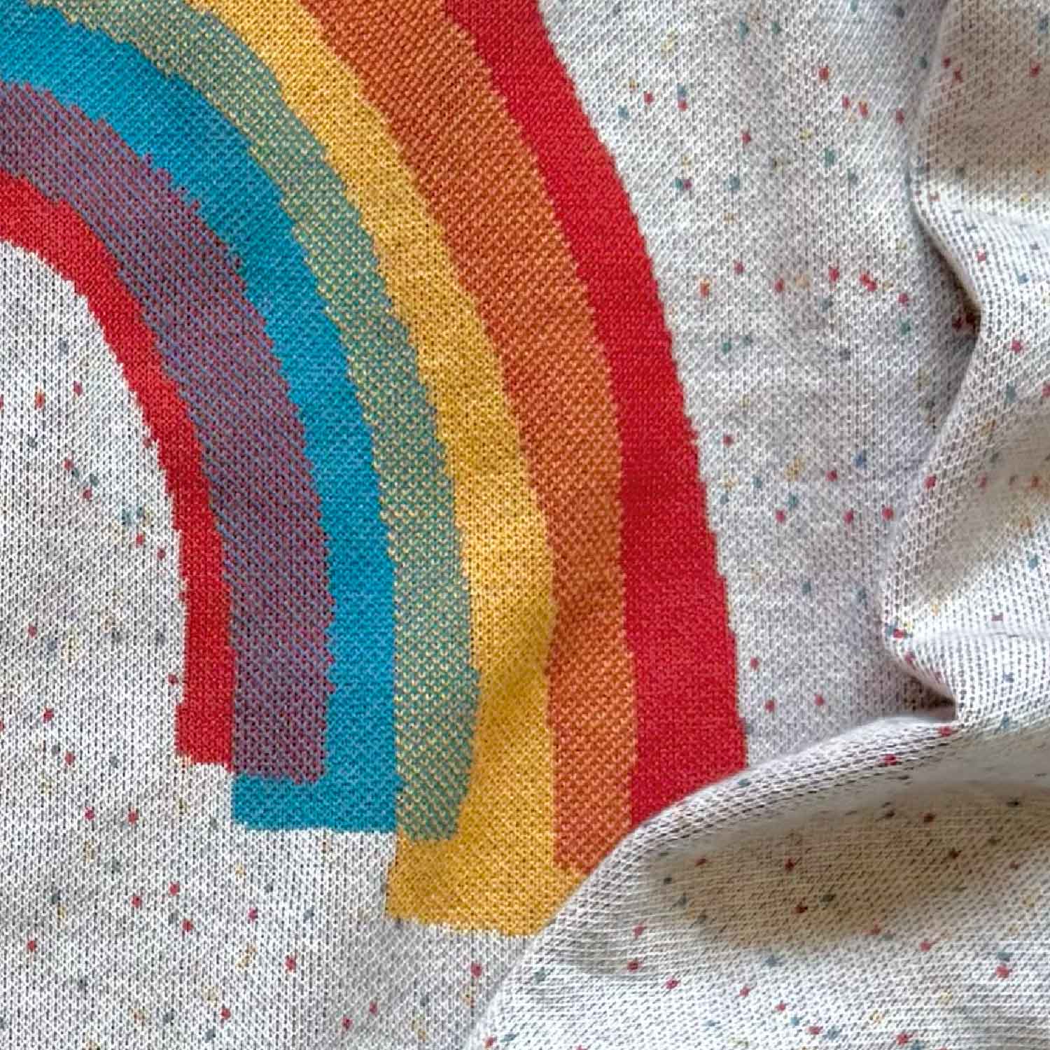Knit detail of a rainbow on a white sweater