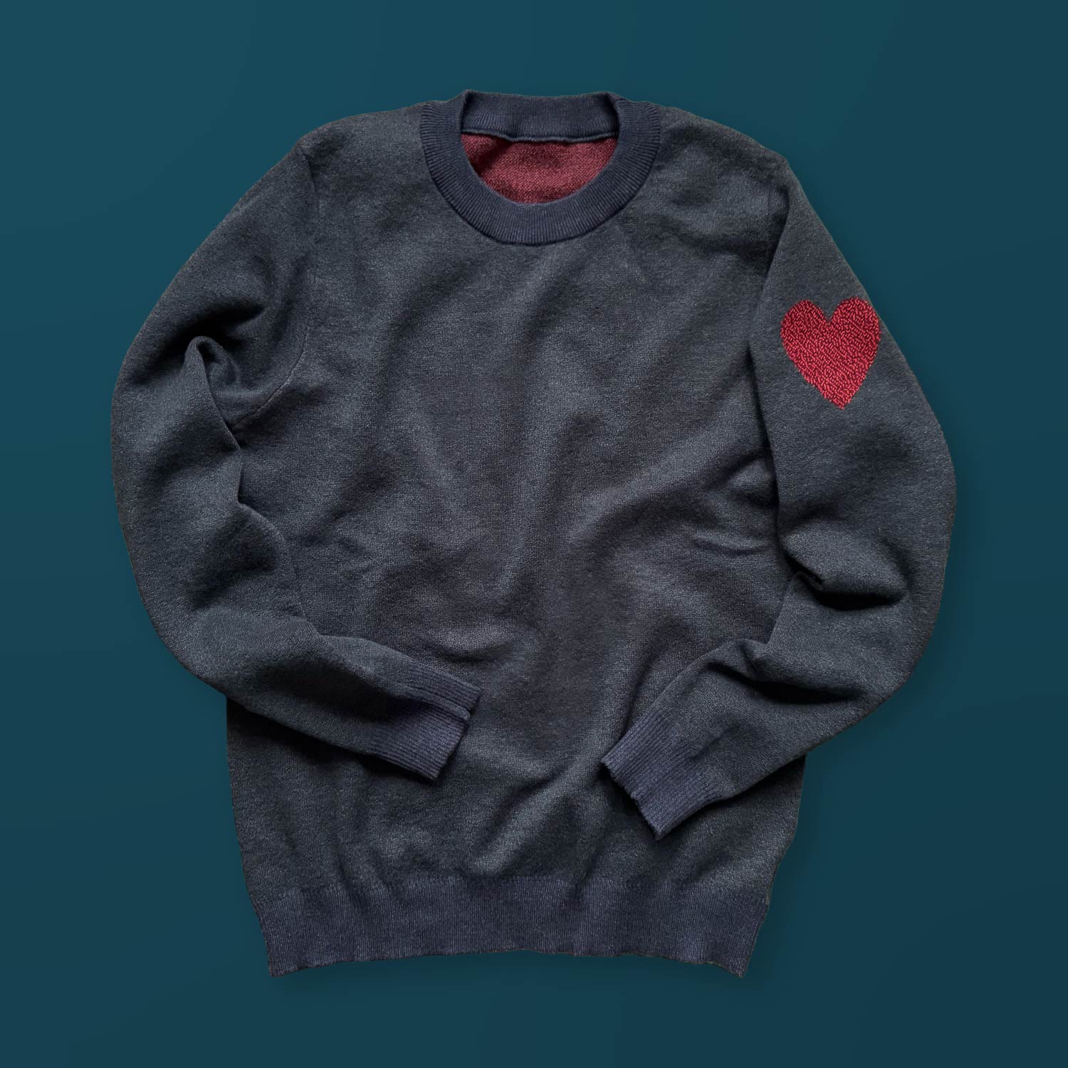 A dark blue sweater with a red heart design on the left sleeve.