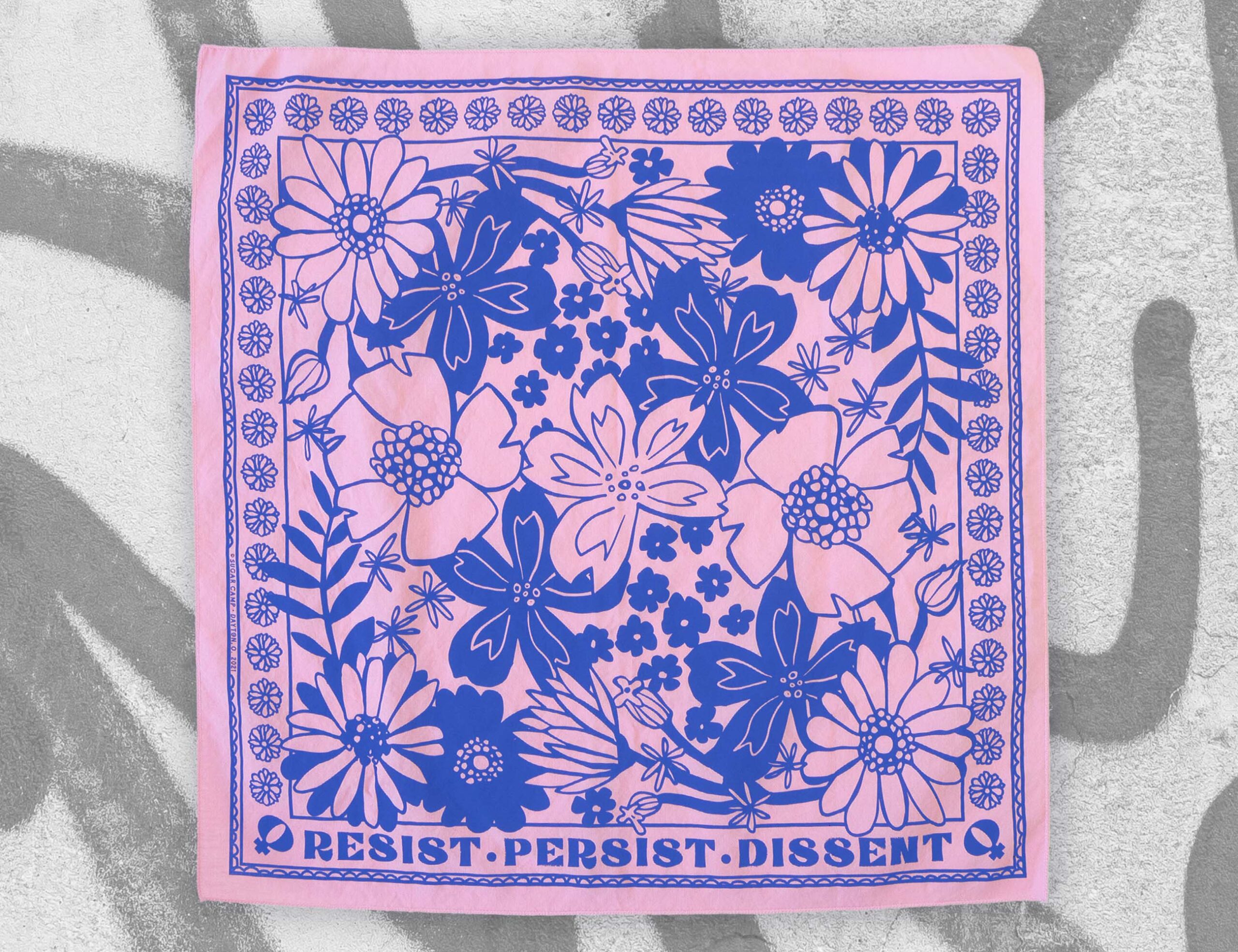 sugar camp resist persist dissent bandana in trans pink & blue lying flat on graphiti background