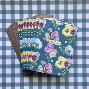Fanned stack of eight blue floral printed thank you cards on a blue plaid background