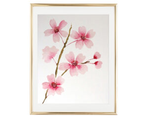 Photo of our Watercolor Cherry Blossom Branch Art Print in a gold frame with a vertical orientation. The art print features a watercolor painting of a single branch of pink cherry blossoms.